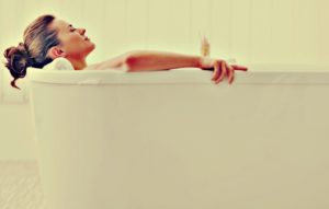 relaxed young woman laying in bathtub